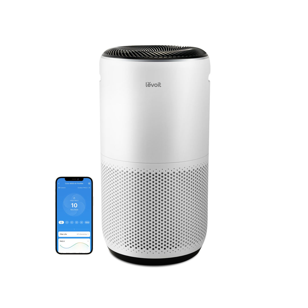 Levoit Core 400S-P white cylindrical smart air purifier next to a phone showing the VeSync app
