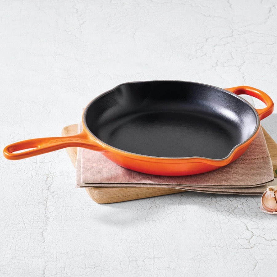 Le Creuset Signature 10.25 inch enameled cast iron skillet in Flame orange with black satin interior and helper handle